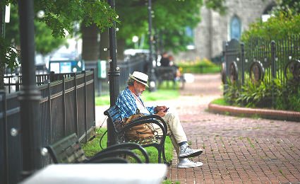 Man sitting on a bench along a tree-lined brick walkway in Baltimore